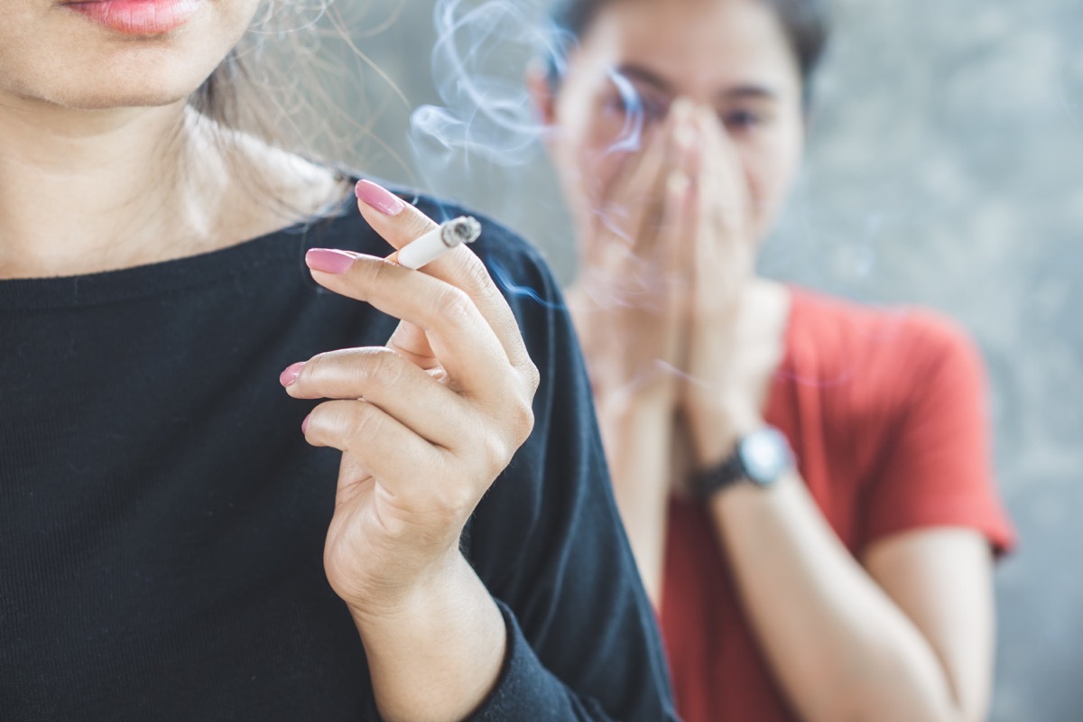 woman smoking cigarette near people