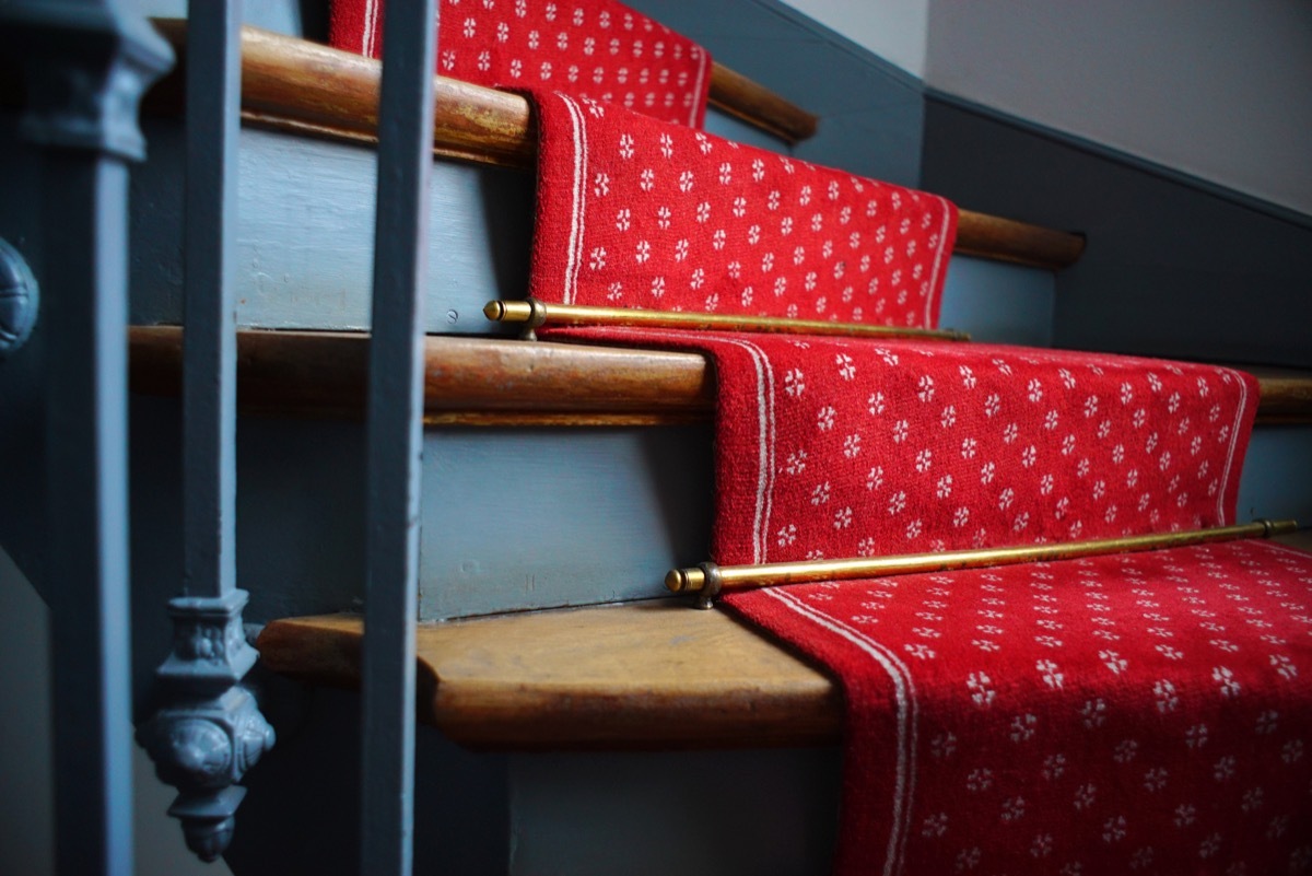 Golden stair rods on a red carpeted staircase