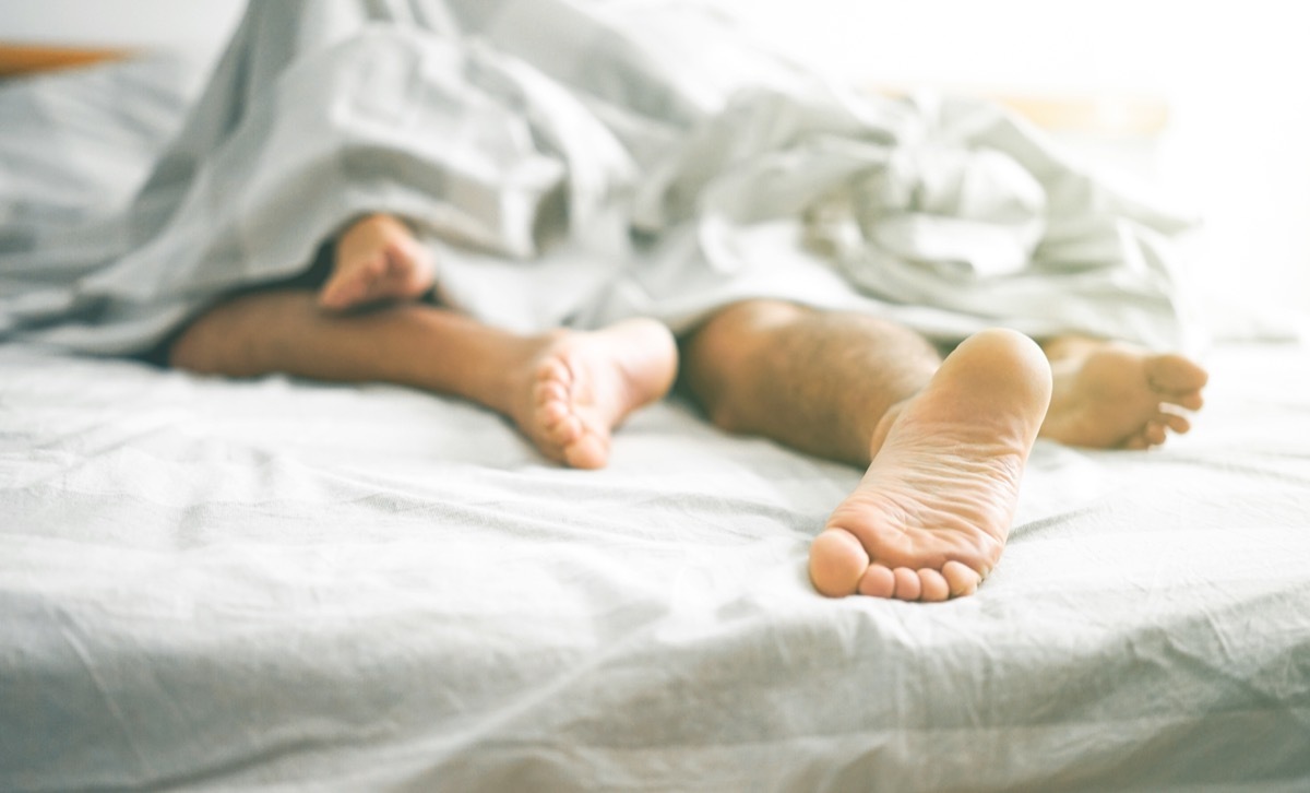 Close up of male and female feet on a bed