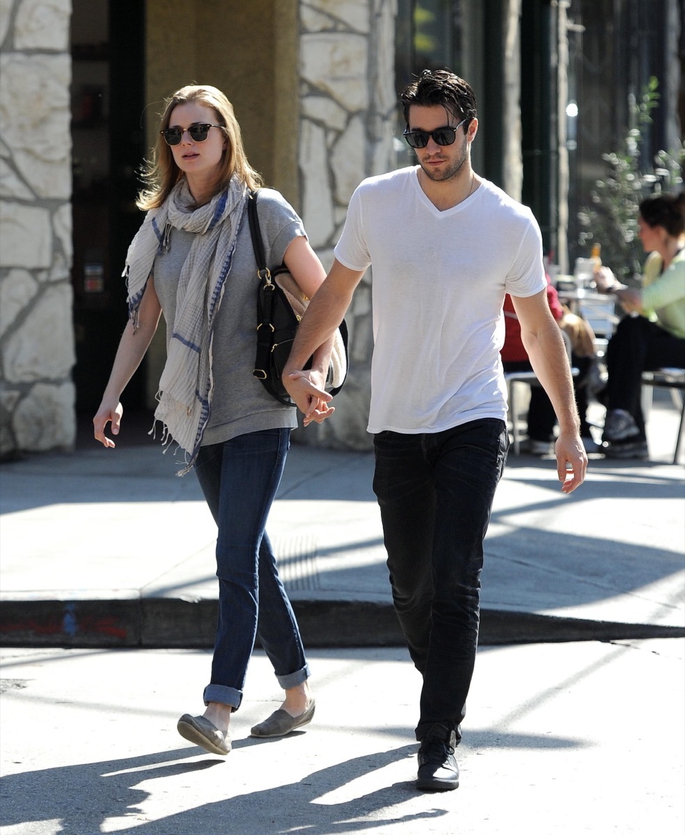 Emily VanCamp and Josh Bowman holding hands while walking down the street