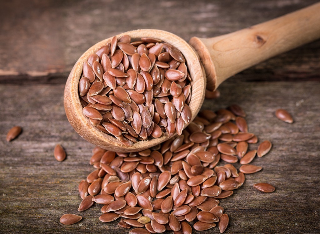 flax seeds pouring out of wooden spoon