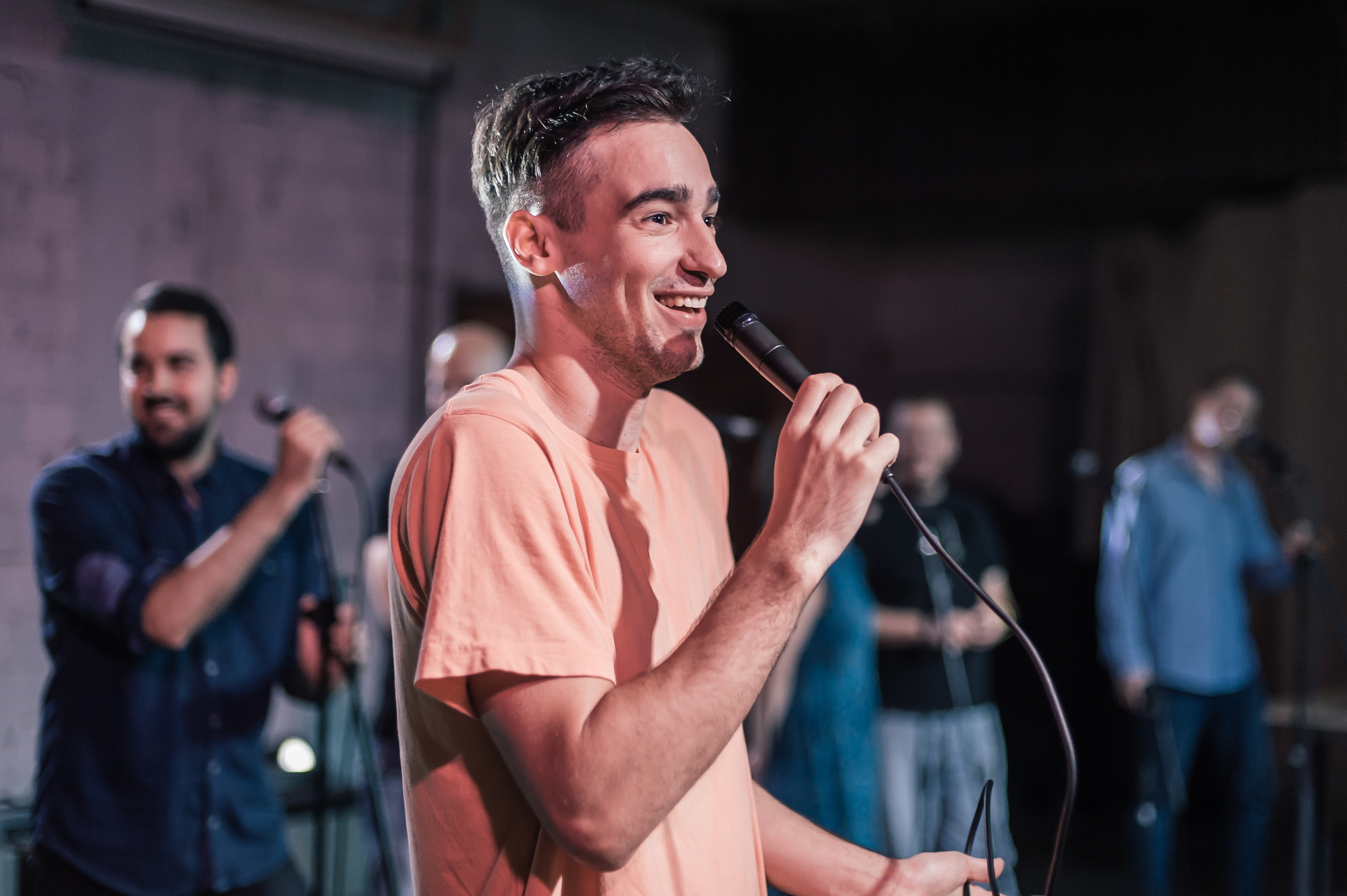 Smiling and witty stand up actor comedian on stage, talking and singing into a microphone and making the audience laugh. Final rehearsal before the premiere and performance in the theater