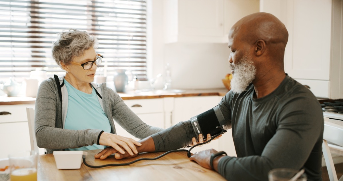 Cropped shot of an affectionate senior woman sitting and checking her husband's blood pressure in their kitchen