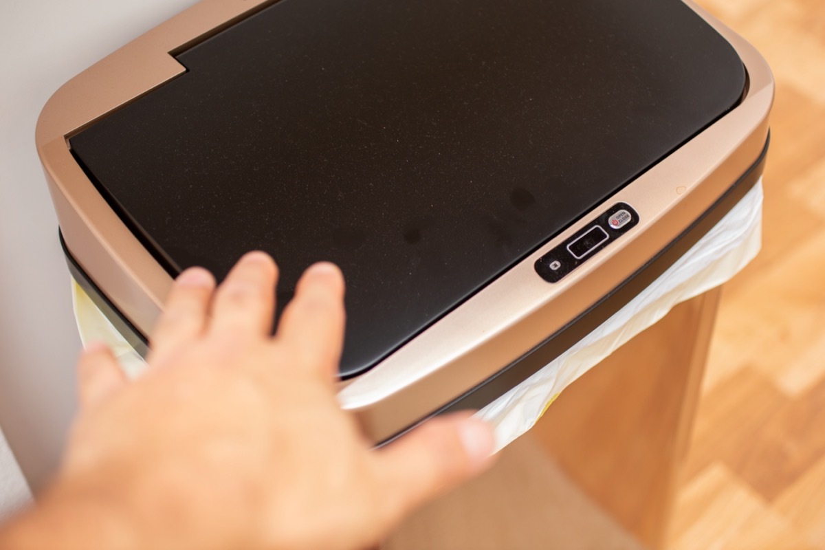 hand reaching toward sensor trash can