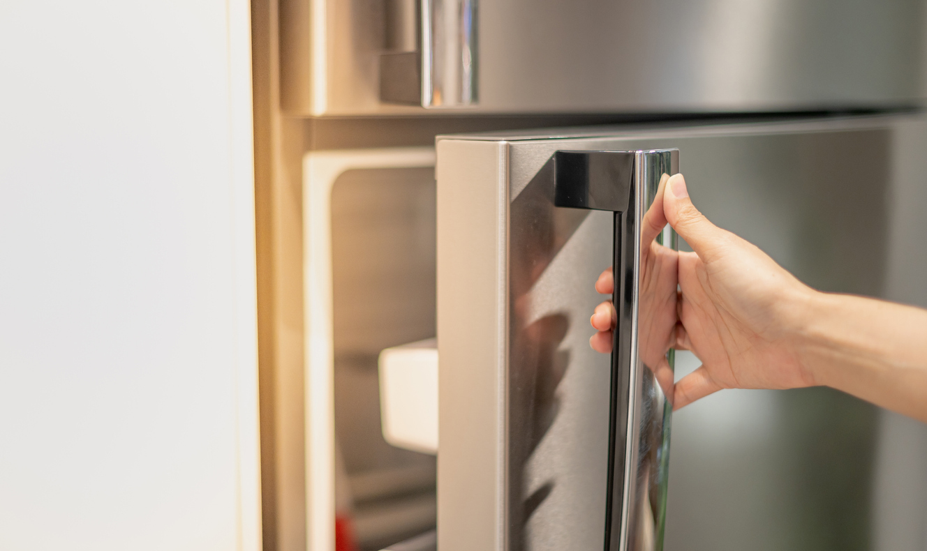 Hand opening a refrigerator door.