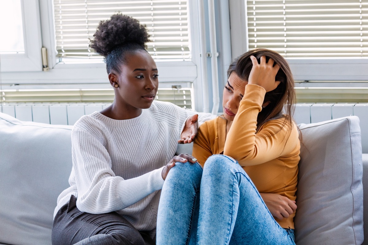 Sad girl and supporting friends trying to solve a problem. Two sad diverse women talking at home. Female friends supporting each other. Problems, friendship and care concept