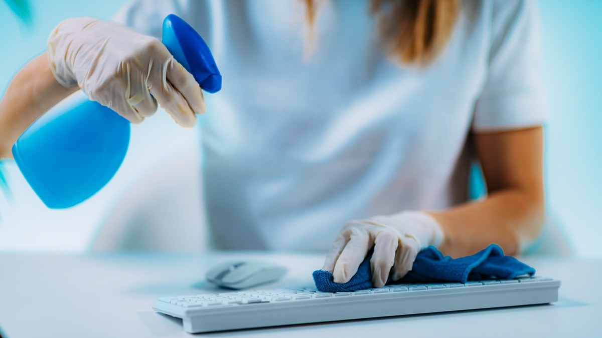 Disinfection of Computer Keyboard and Mouse. Woman disinfecting Computer Keyboard and Mouse with Alcohol-based disinfectant