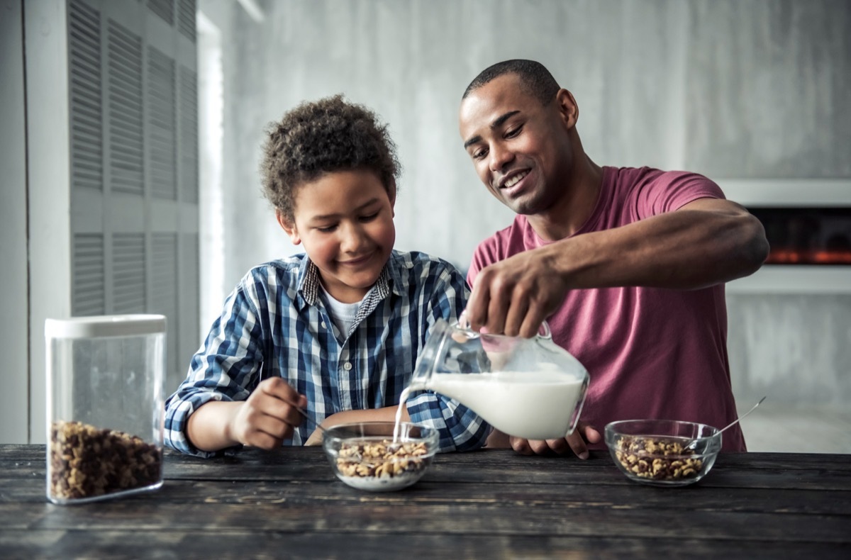 father pouring milk into his son's cereal