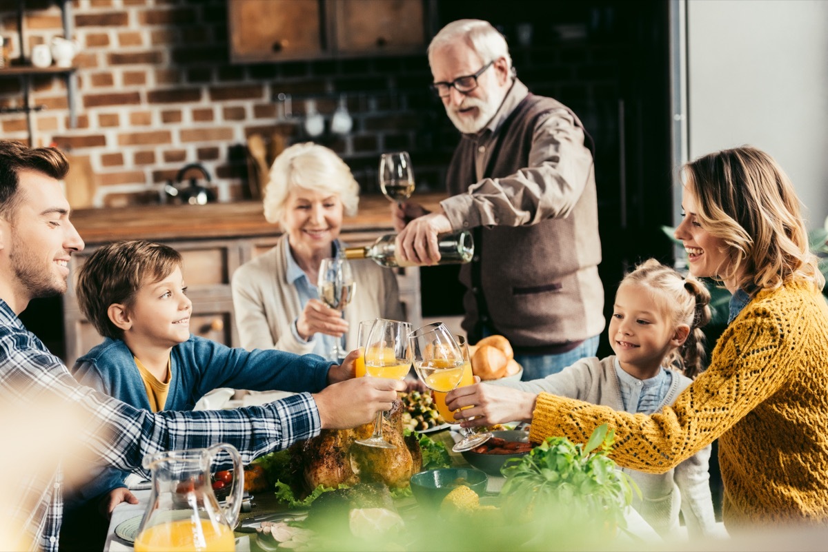 family sitting around a table and eating and drinking for thanksgiving meal