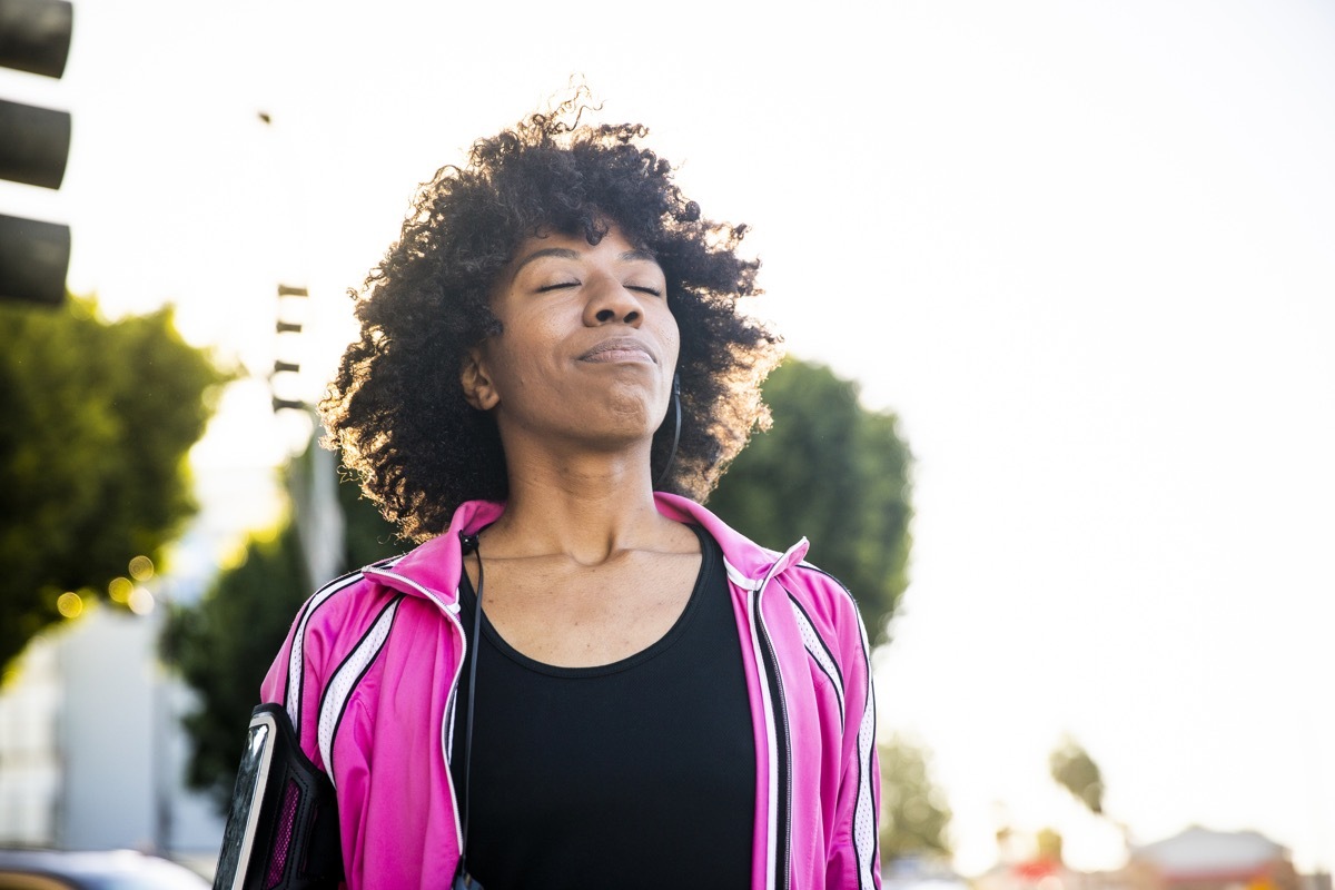 Black woman takes deep breath outdoors