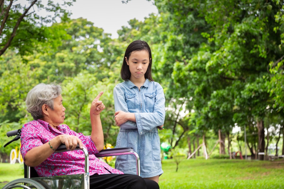 upset grandmother in wheelchair scolding granddaughter