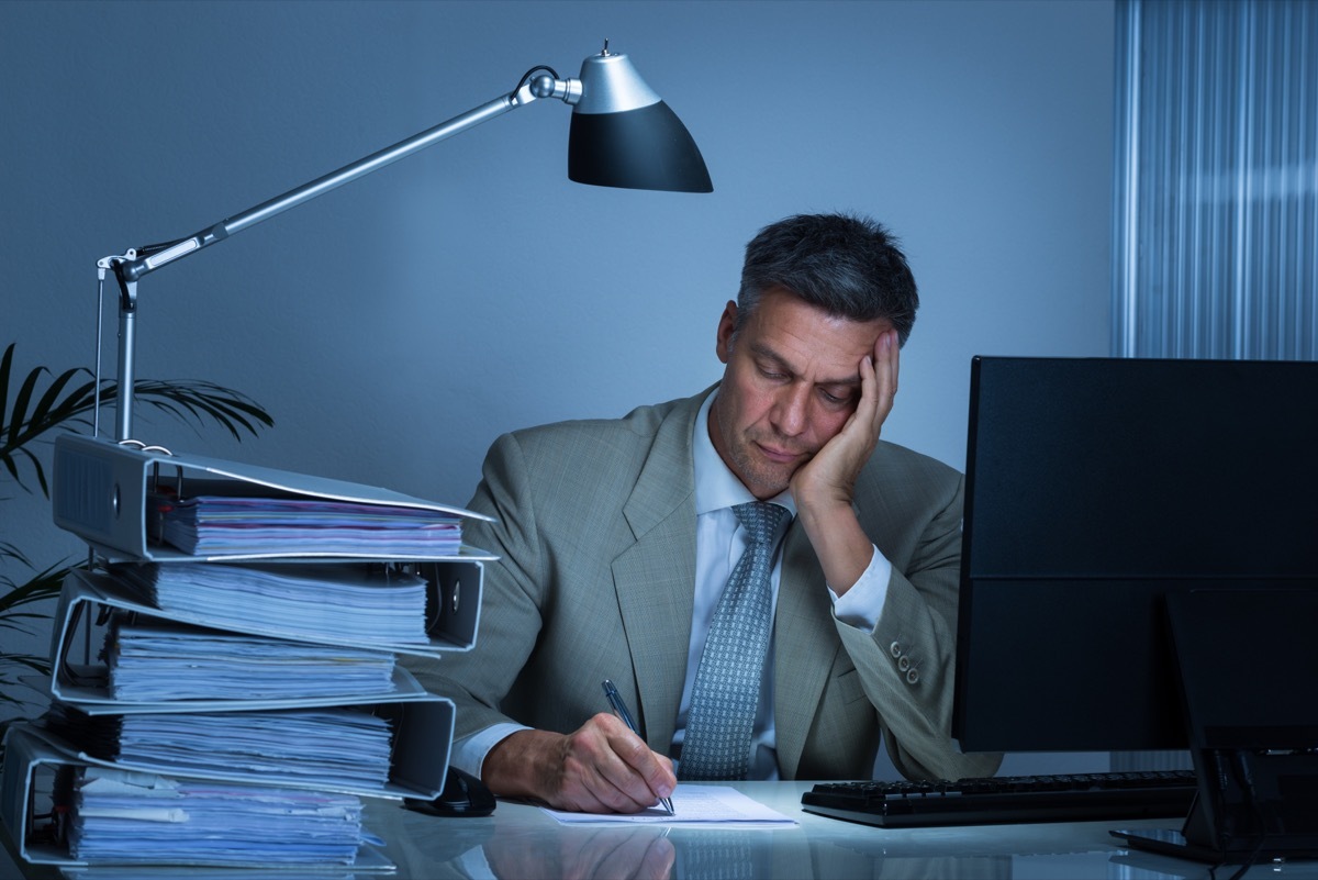 Man Writing at His Desk Feeling Sad Signs of Burnout