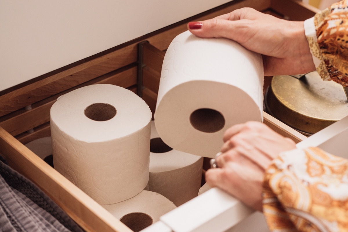 Toilet paper storage in bathroom drawer Photo of female hand grabbing a new roll