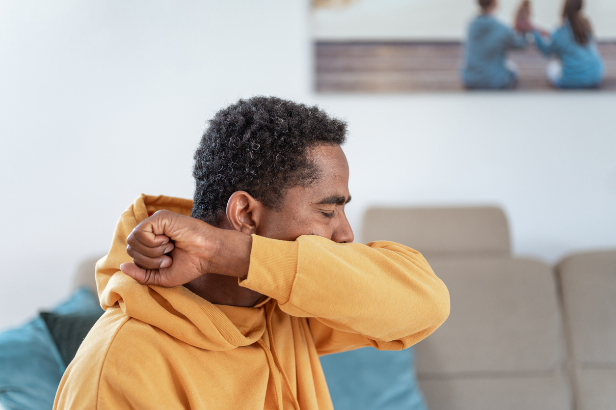 Man coughing into the crook of his arm. 