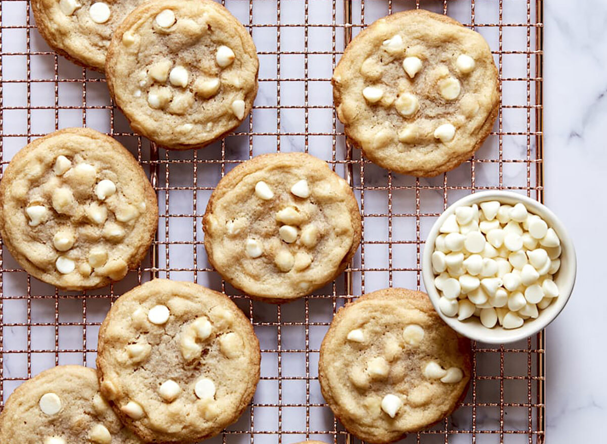 lemon white chocolate cookies on cooling rack with bowl of white chocolate chips