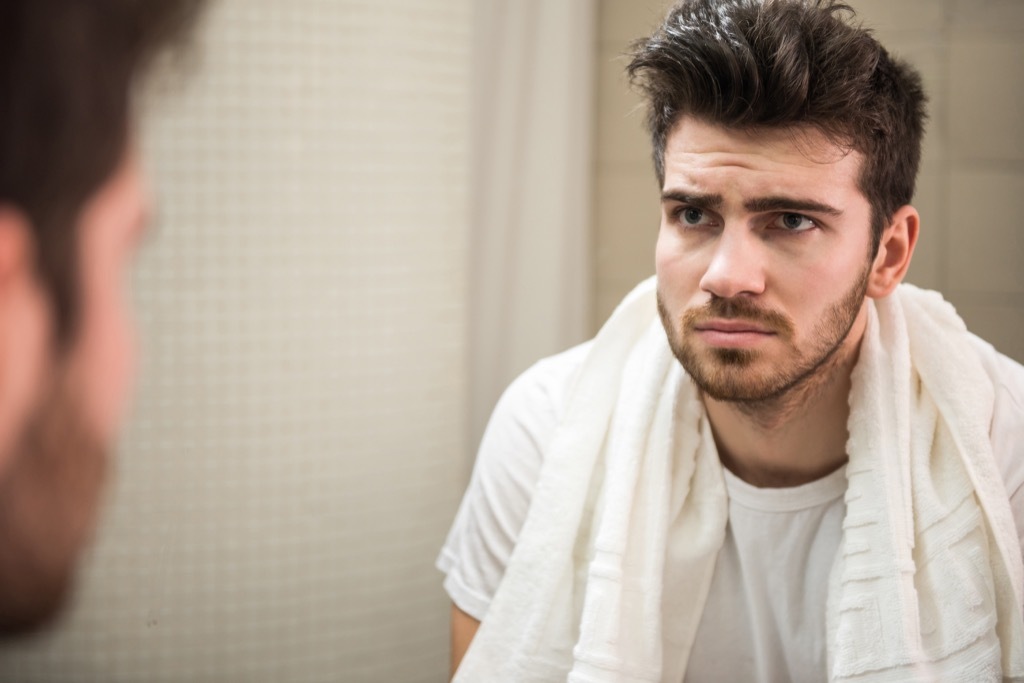 Man looking in mirror feeling insecure