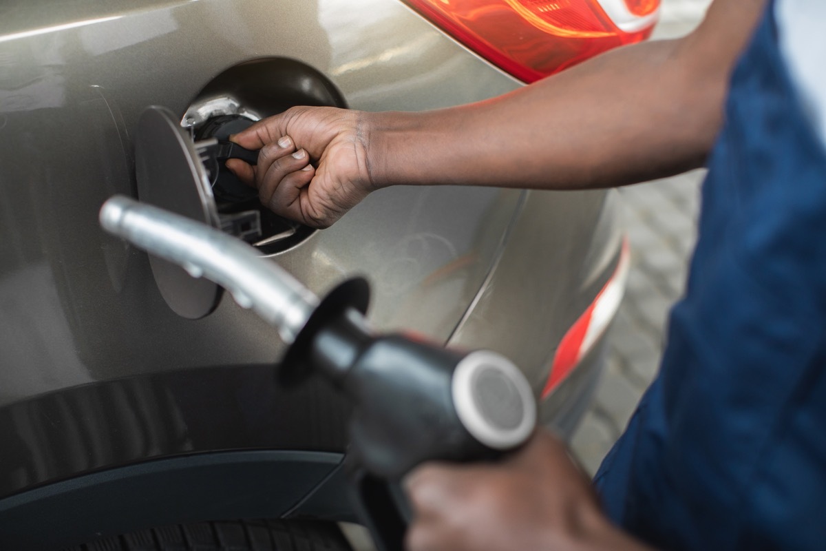 Close up cropped shot of a gas station worker's hands with filling gun, ready to refueling the car with gas or petrol at a gas station