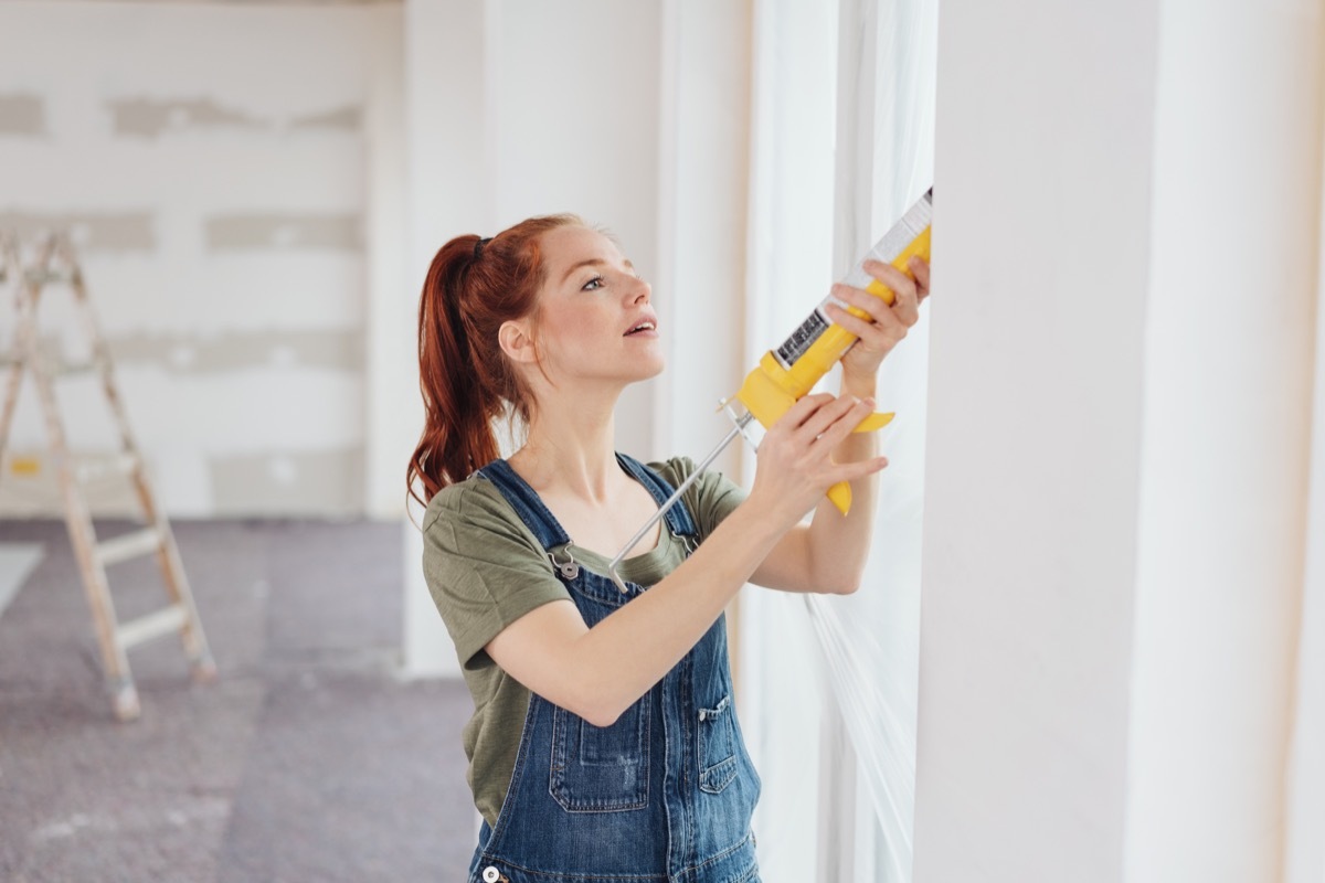 redheaded woman caulking window