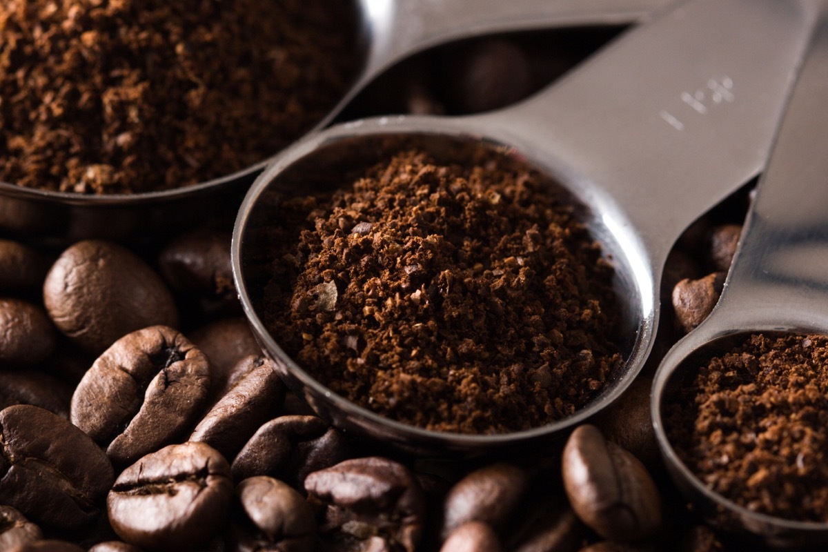 Measuring spoons with ground coffee and coffe beans.