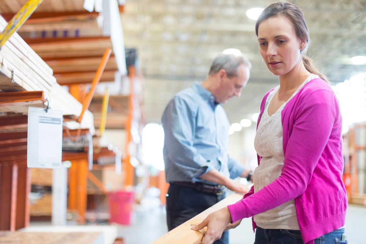 Woman picking up 2x4 boards in hardware store