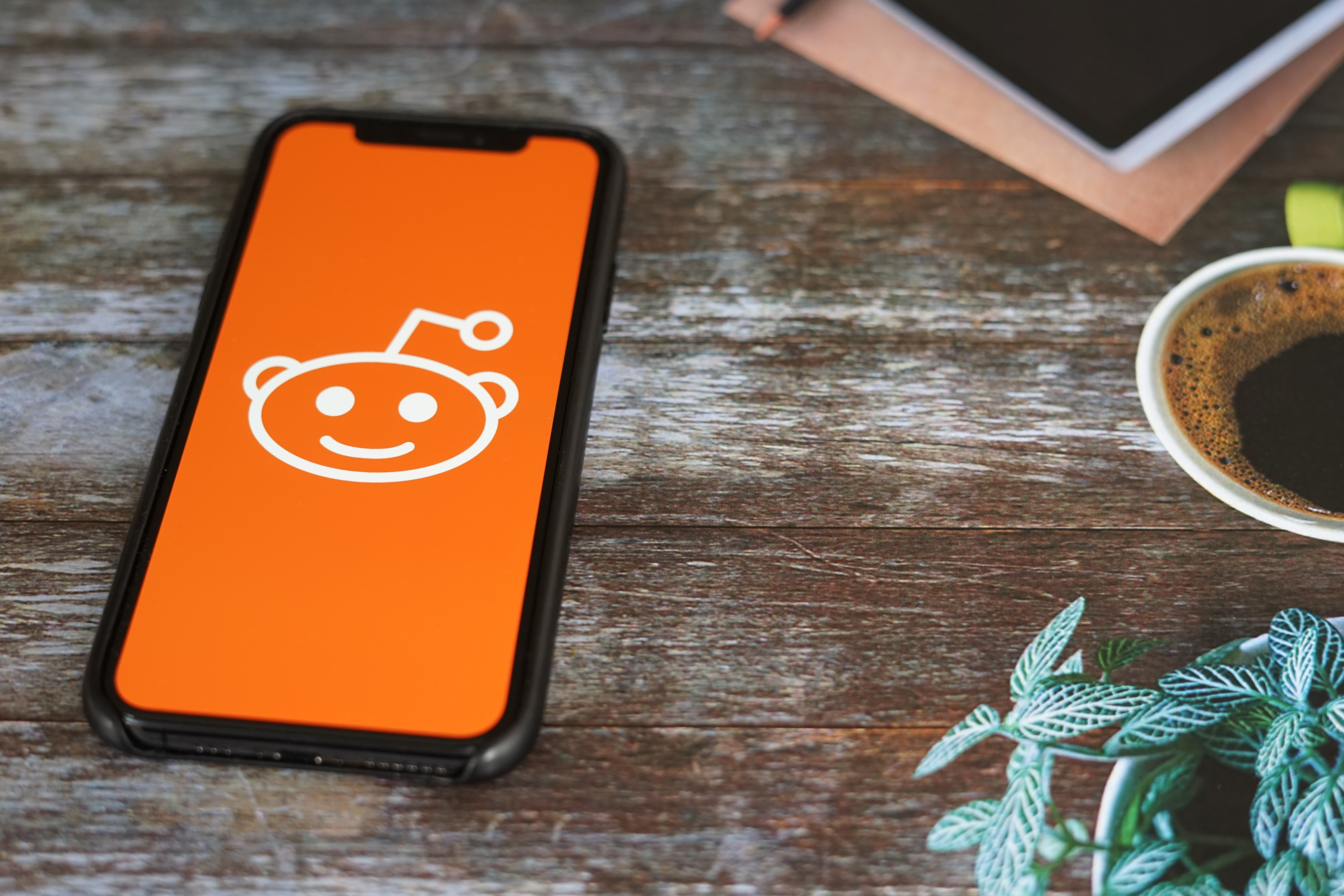 phone on table opening the Reddit app