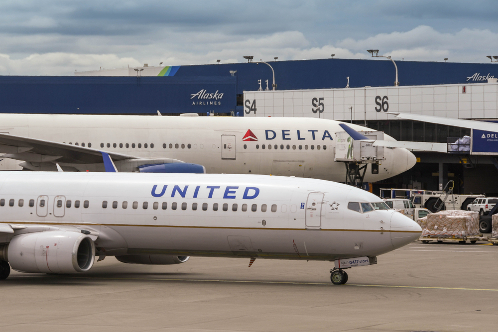 A Delta plane and United plane sitting next to each other on a runway at an airport