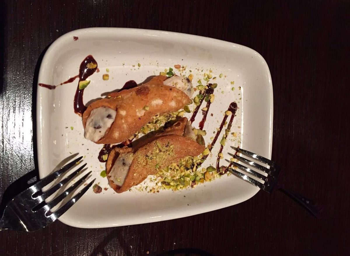 carrabbas traditional cannoli with two forks on white plate