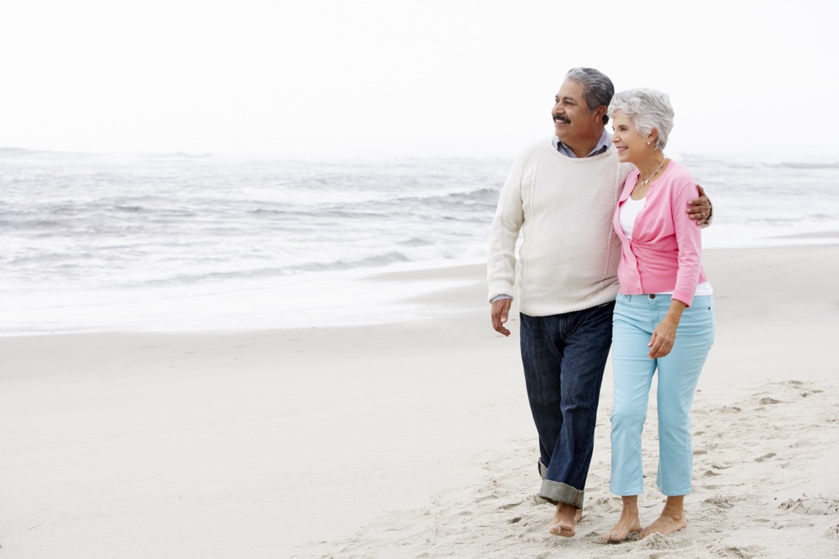 older hispanic couple walking on the beach