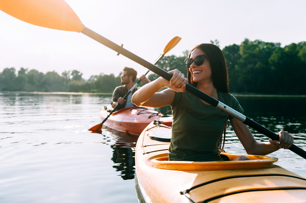 Beautiful young couple kayaking on lake together and smiling