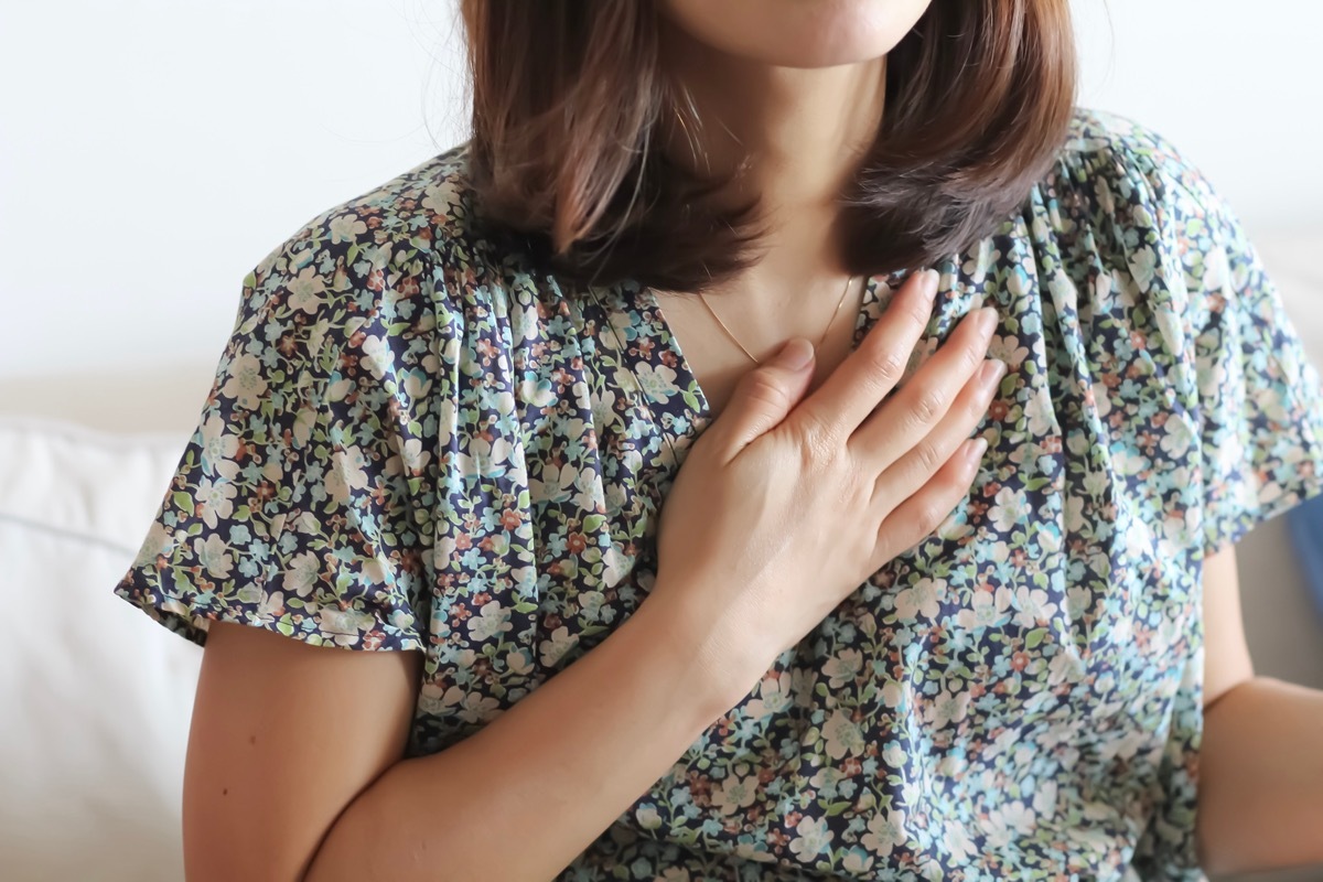 Woman in the casual wear raise her hand over her heart.