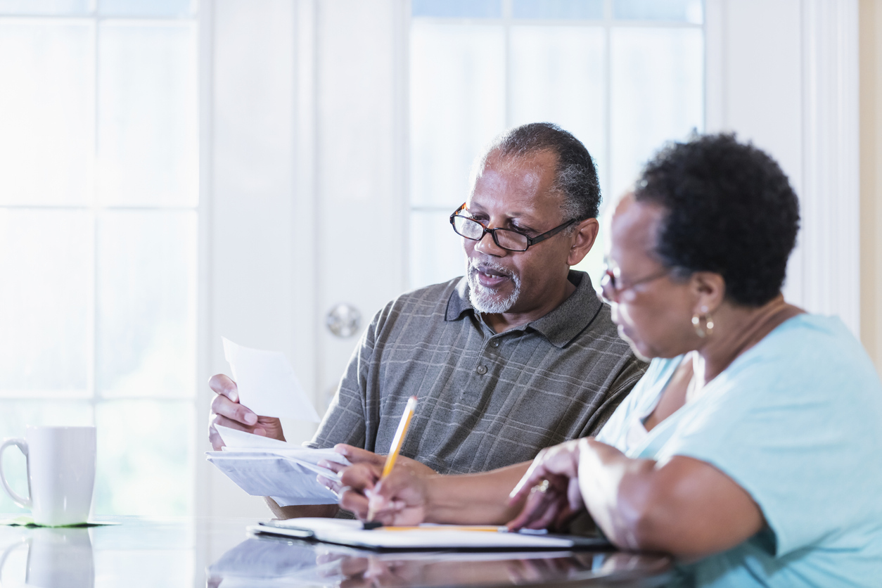 Senior couple sitting at a table going through documents. 