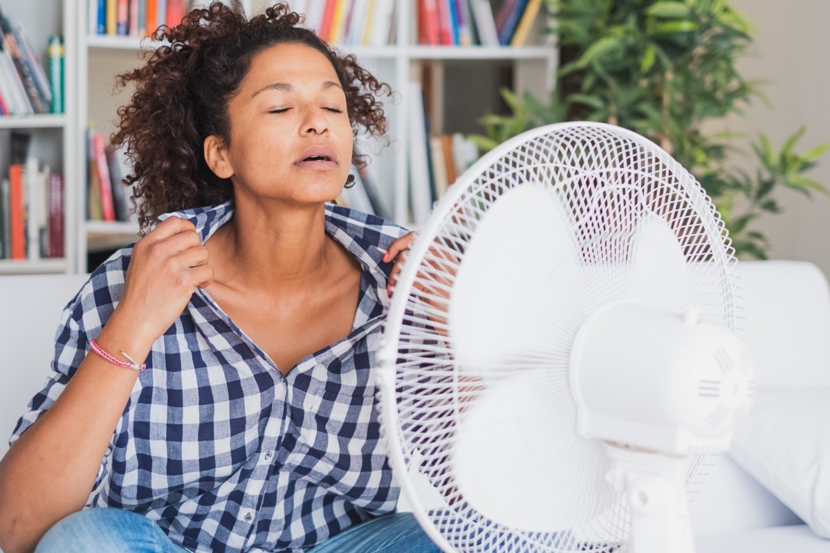 Woman using fan because she has heat intolerance