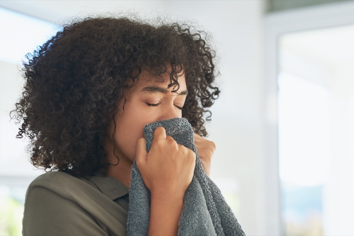 Shot of a young woman smelling freshly washed towels while doing laundry at home