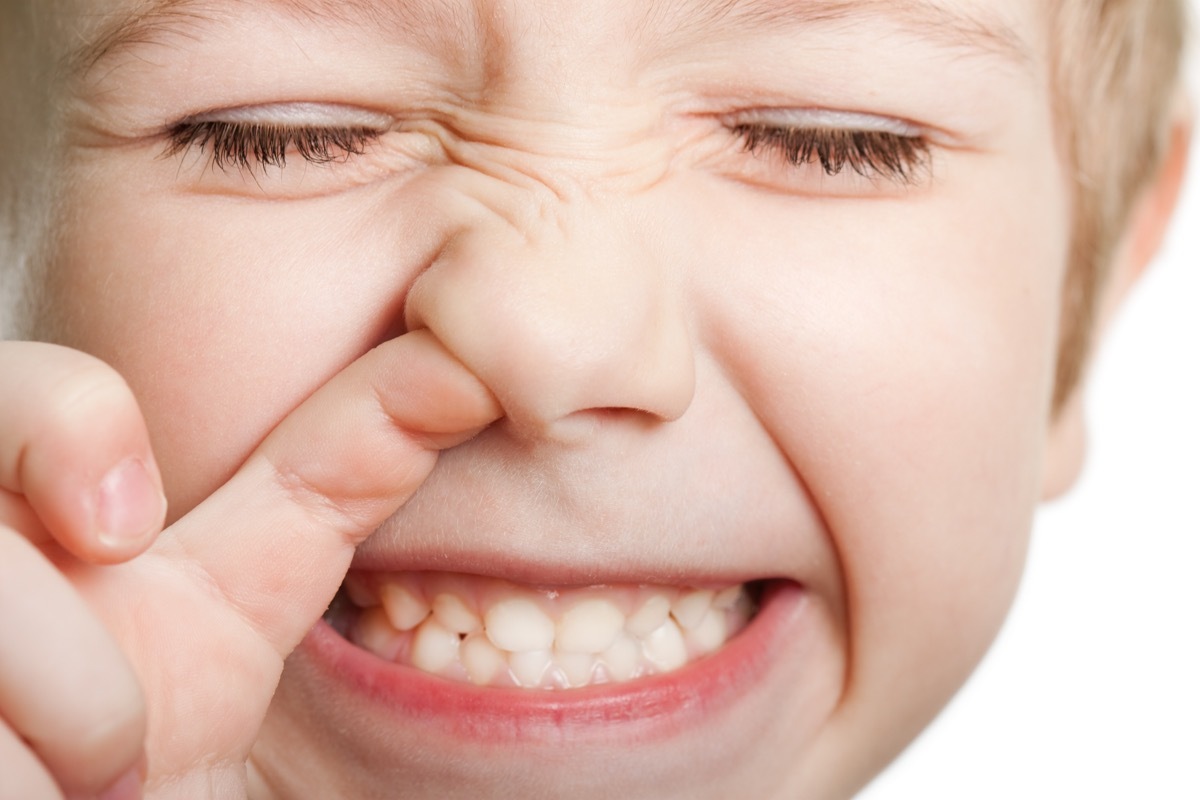 Closeup of young white boy picking his nose while smiling