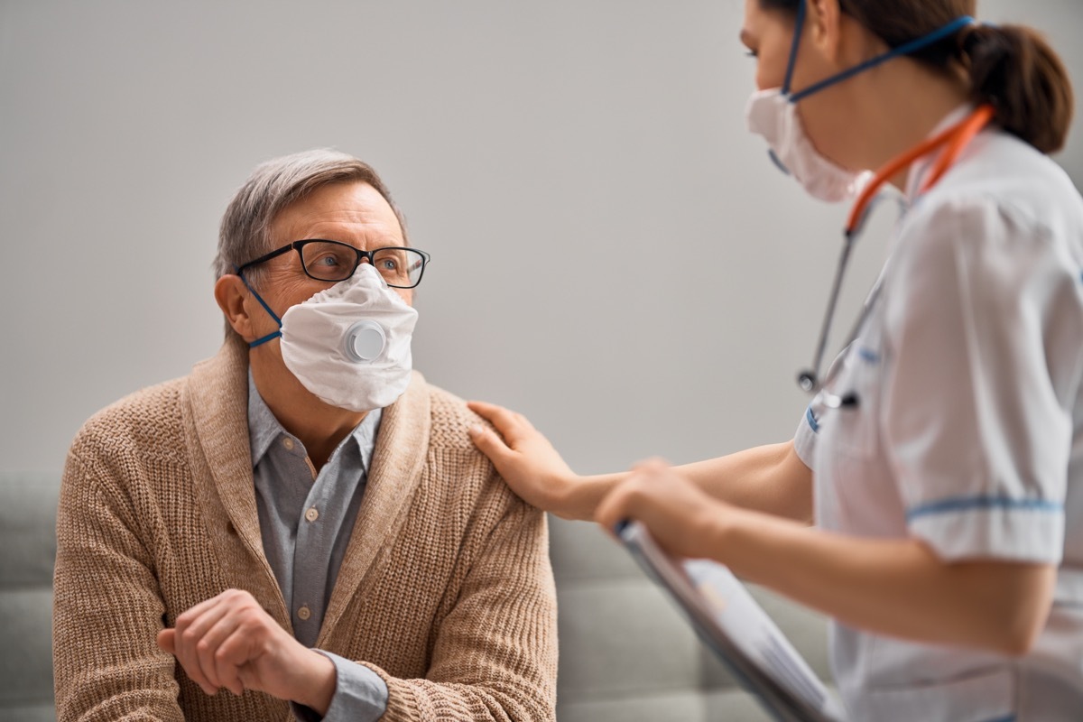 young doctor or nurse taking care of elderly white man with coronavirus