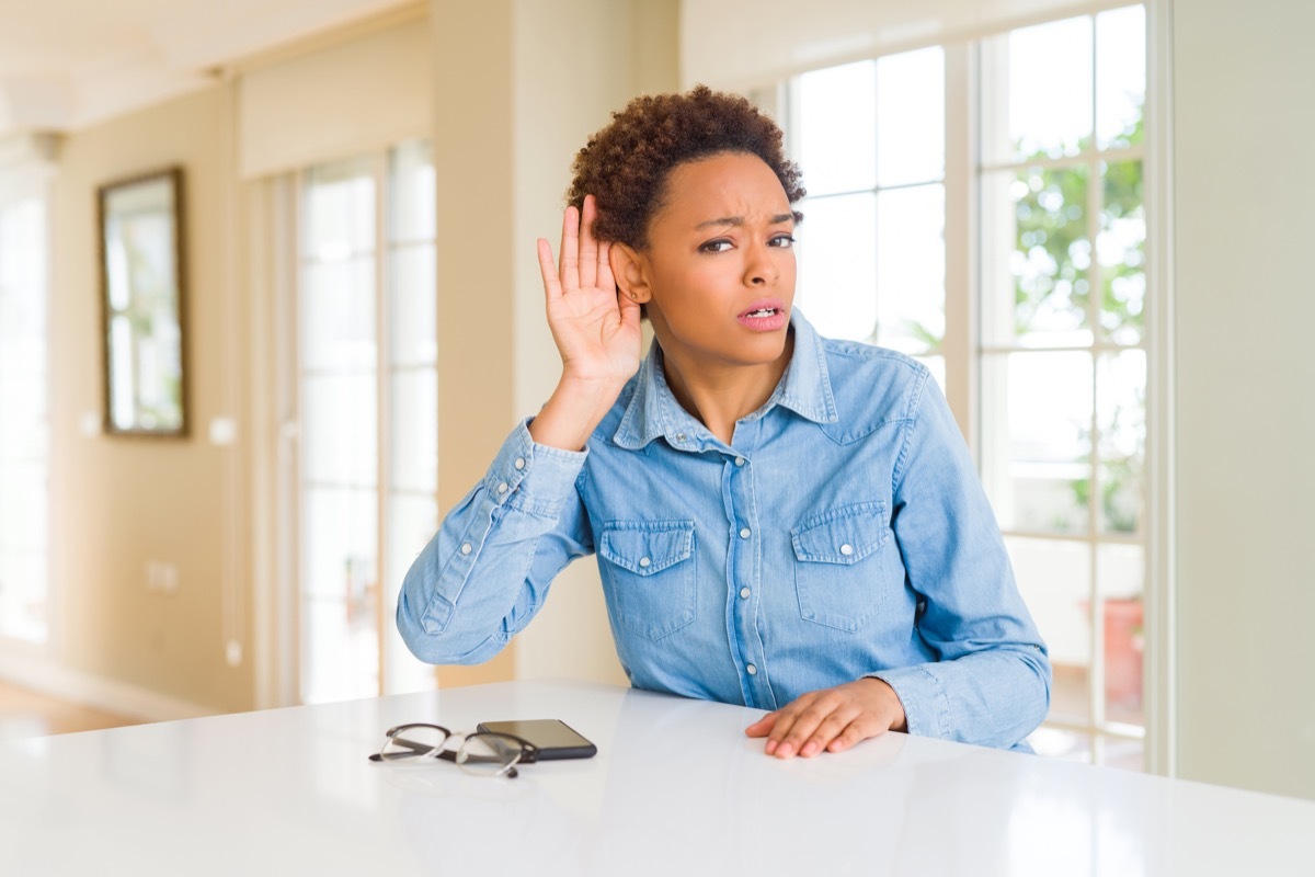 woman smiling with hand over ear listening an