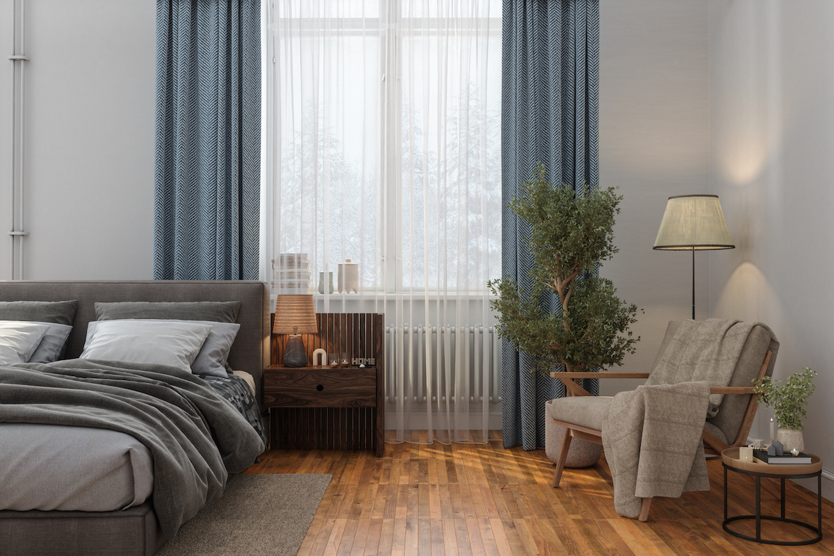 Bedroom Interior With Messy Bed, Nightstand, Armchair And Floor Lamp