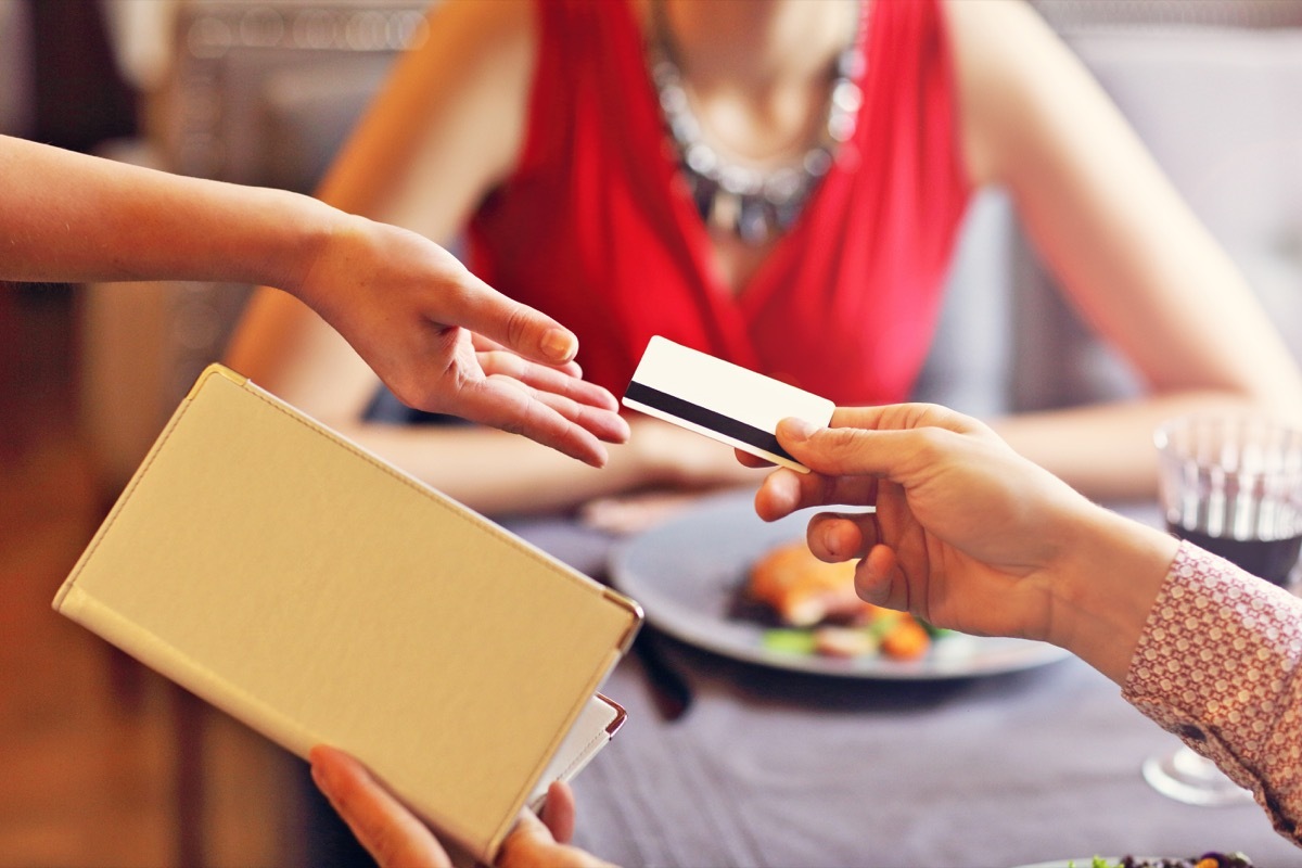 man handing credit card to waitress on date