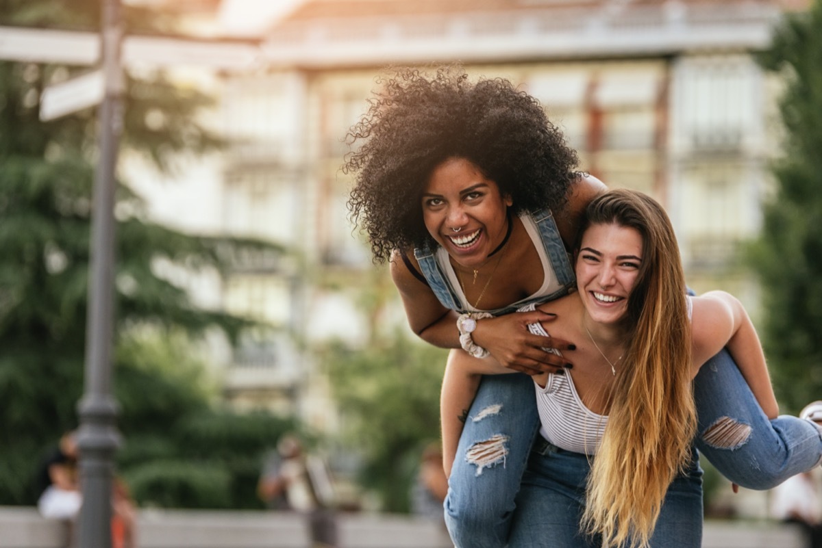 Young woman giving her girlfriend a piggyback ride