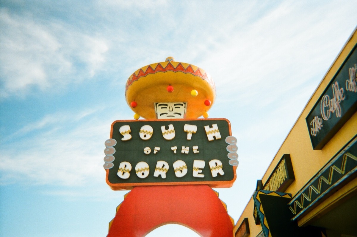 statue of man holding south of the border sign