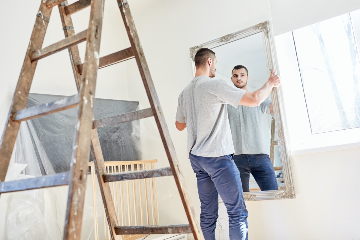 young white man hanging mirror