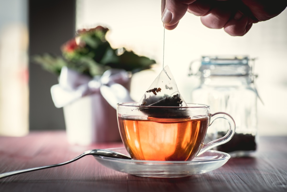 Putting tea bag into glass cup full of hot water