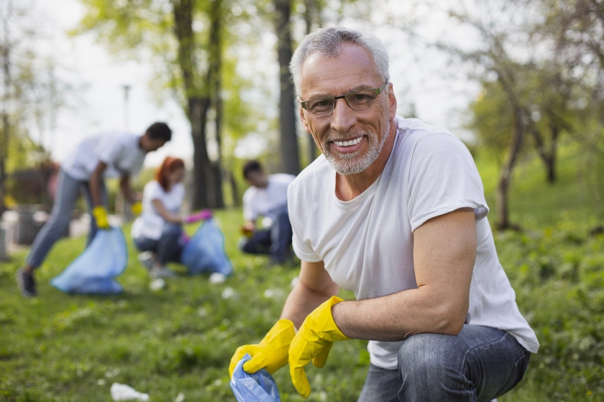 Work as volunteer. Experienced senior volunteer holding garbage bag