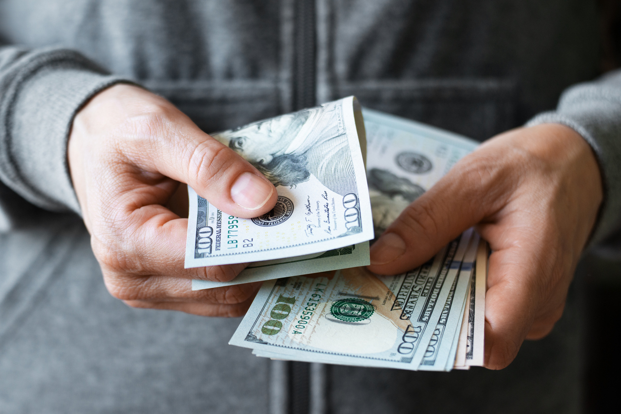 A close up of hands holding $100 bills