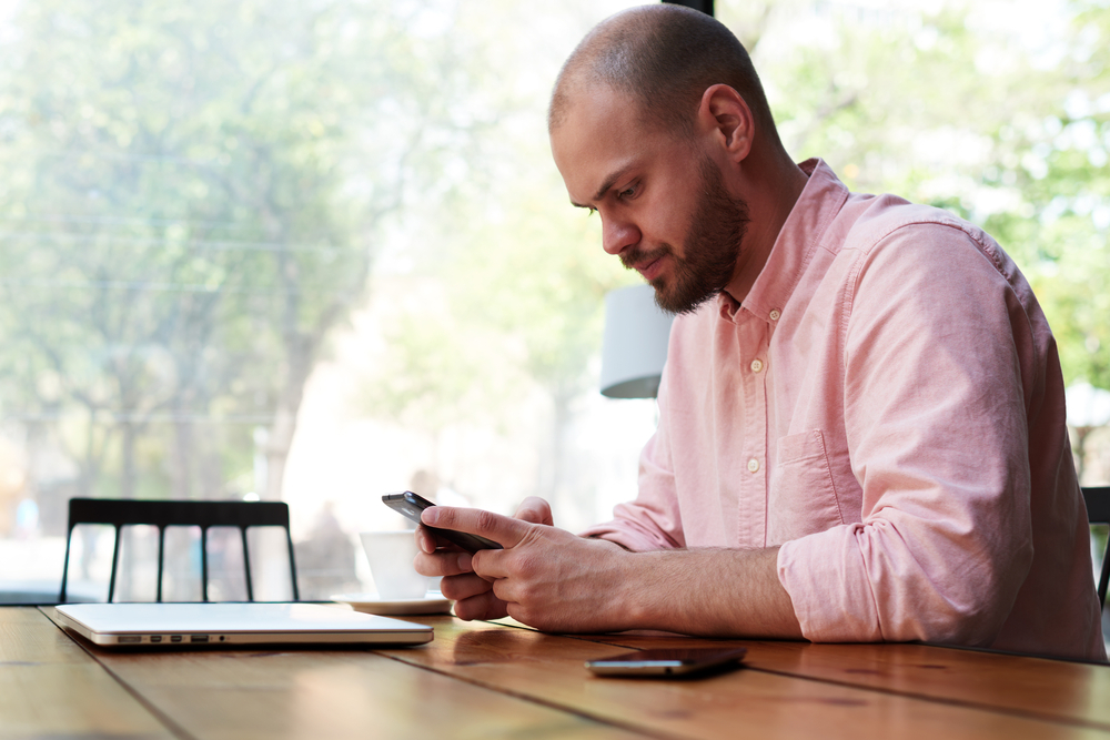 A young man using an Android phone in a coffee shop