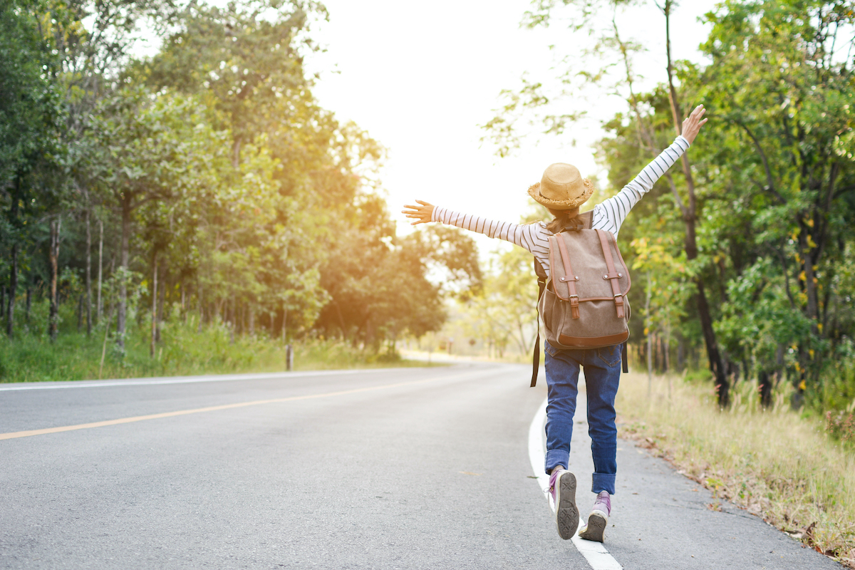 Happy Asian girl backpack in the road and forest background, Relax time on holiday concept travel ,color of vintage tone and soft focus