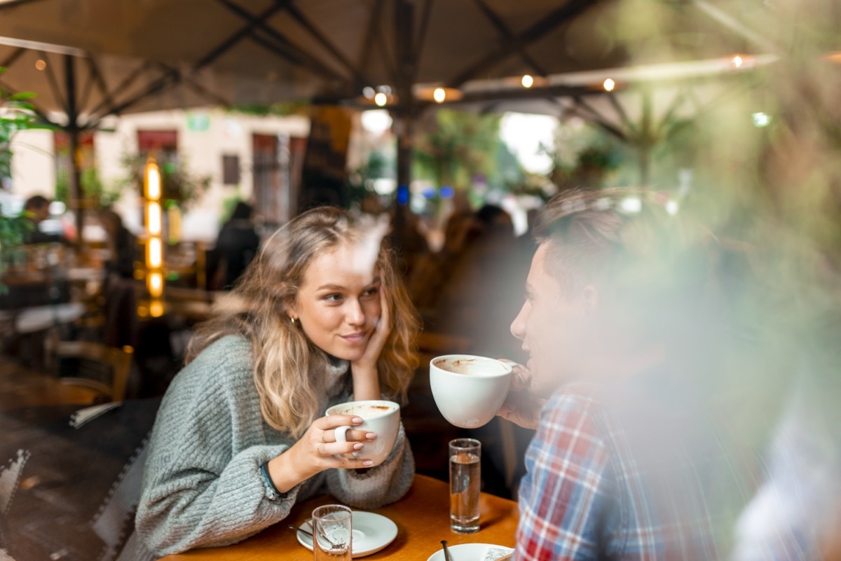 young couple enjoying their coffee in a bar as a view through the window.