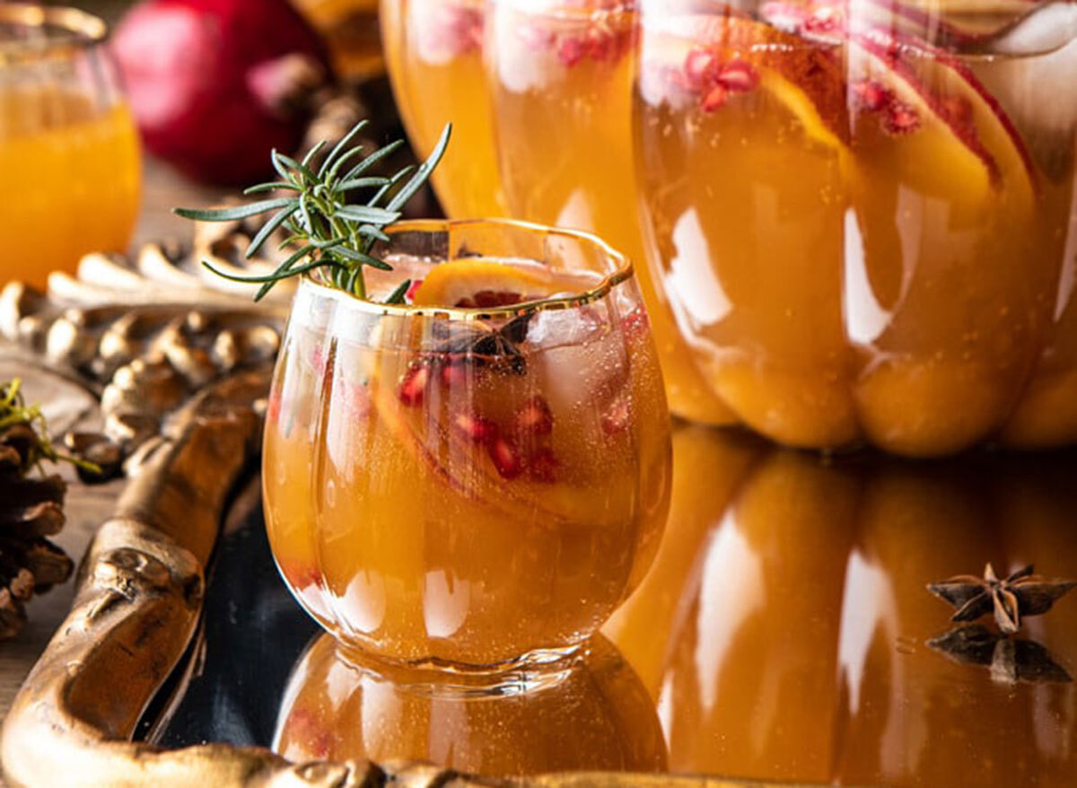 glass of thanksgiving sangria next to pumpkin shaped cauldron on gold serving tray